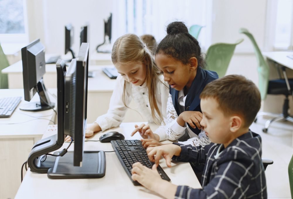 Guy and the girl are sitting at the table. African girl in computer science class. Kids playing computer games.